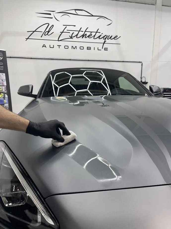 Carrosserie noire après traitement céramique, reflets miroir sous l'éclairage d'atelier