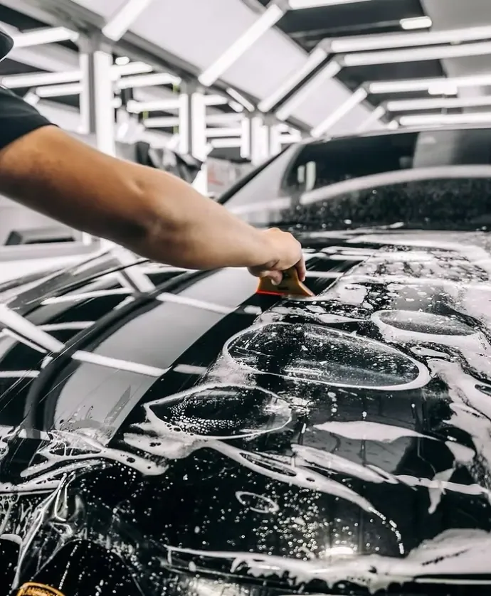 Détailleur au travail sur la carrosserie d'un véhicule premium dans l'atelier de Barchon