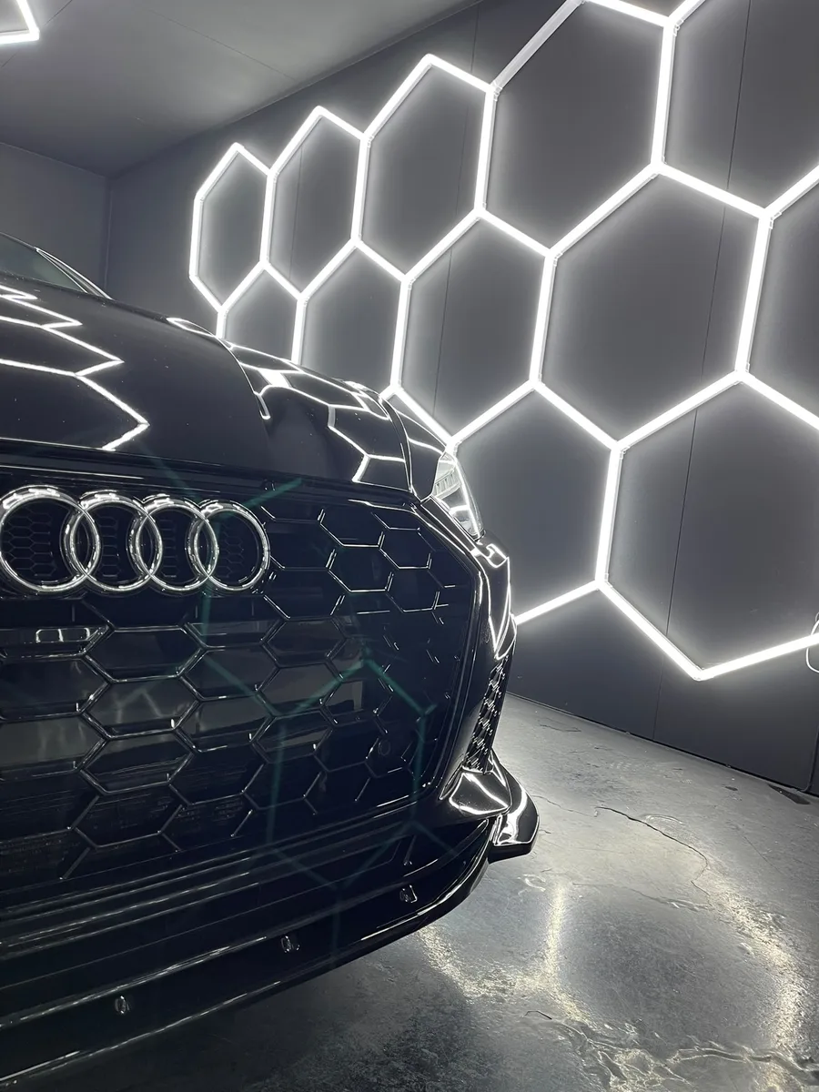 Audi RS noire, face avant sous l’éclairage hexagonal de l’atelier