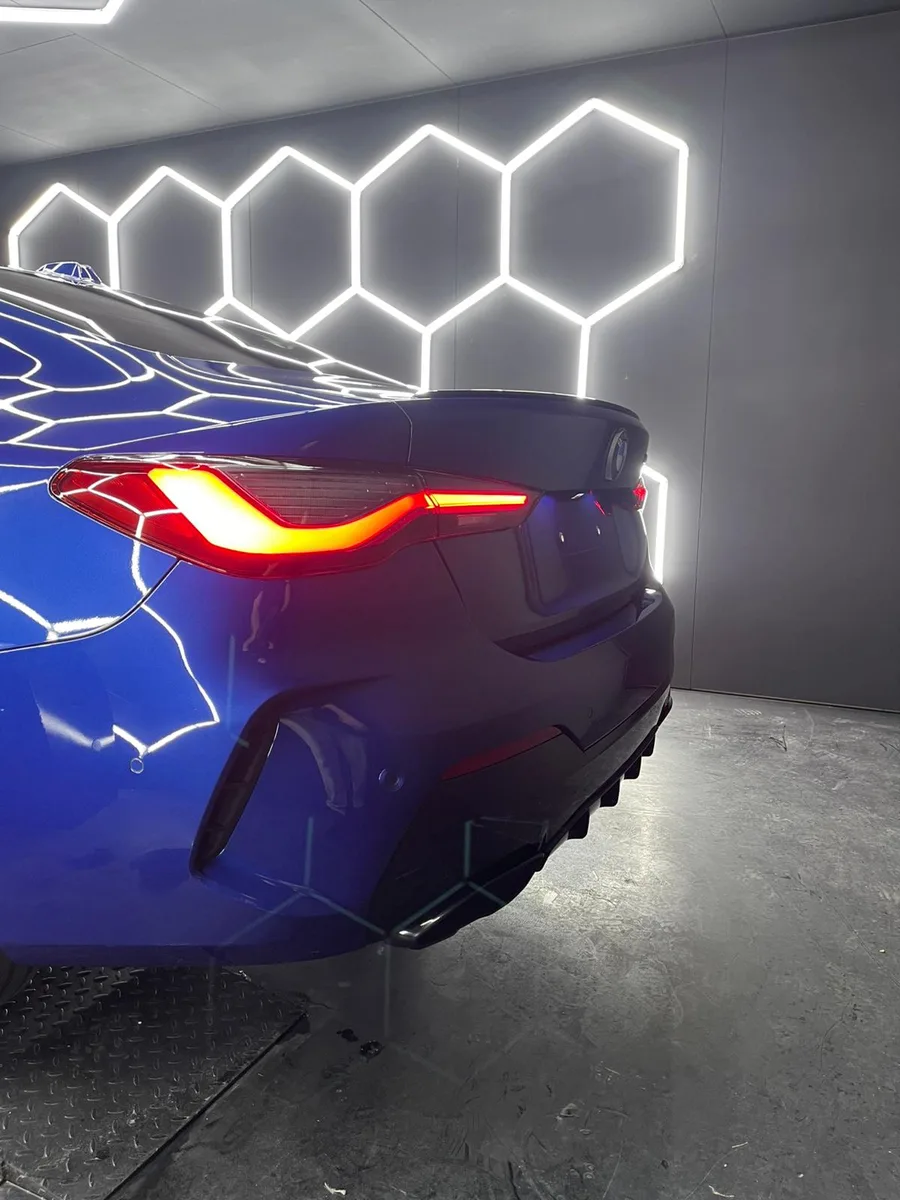Feu arrière allumé dans l’obscurité de l’atelier, reflets sur la carrosserie