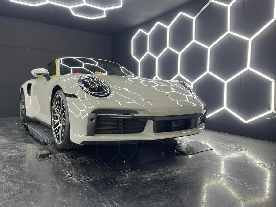 Porsche 911 Turbo S cabriolet blanche, capot ouvert sous les hexagones lumineux