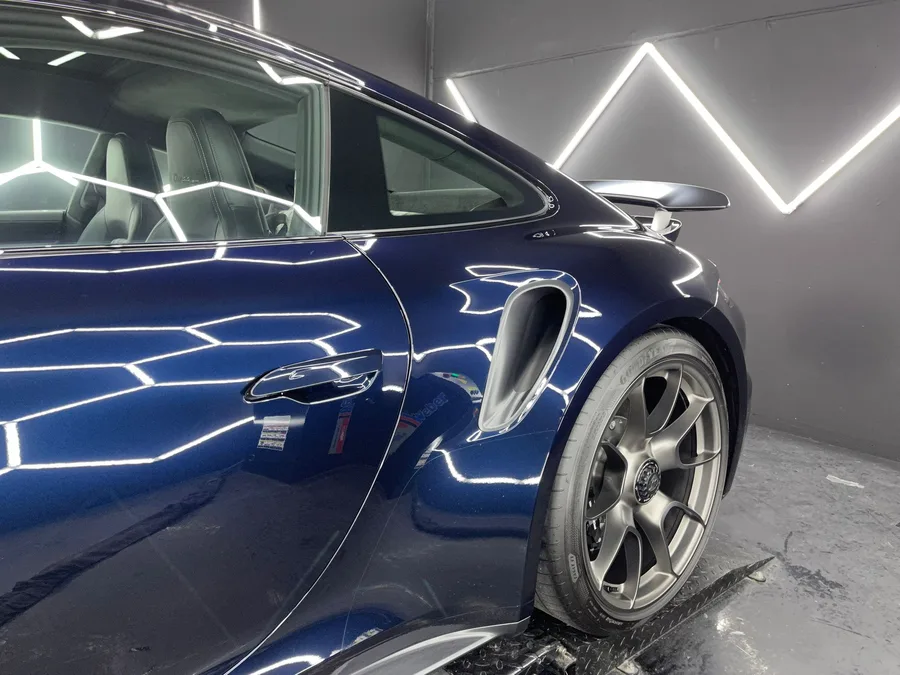 Porsche 911 GT3 bleu marine, profil complet sous les hexagones lumineux